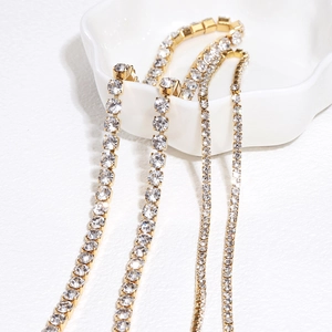 Sparkling gold plated tennis chain with white cubic zirconia on a white ceramic tray