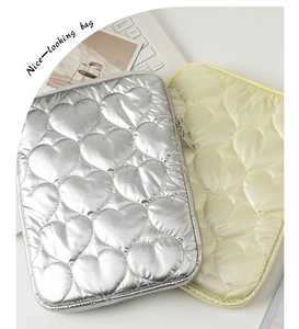Close-up of heart-quilted laptop sleeves in metallic silver and cream yellow finishes