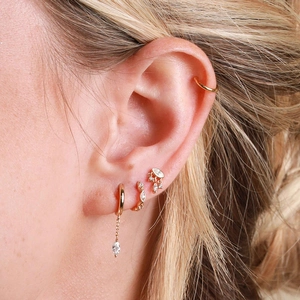 Detail of gold ear cuff and horse-eye pendant earrings set with sparkling crystals