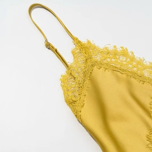Detail of adjustable straps and feather-like eyelash lace on yellow satin midi dress