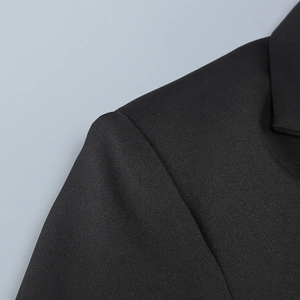 Detail of shoulder pads and notch lapel on a black tailored blazer with woven texture