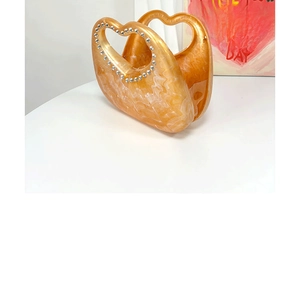 Detail view of heart-shaped handle with rhinestone trim on marble pattern acrylic bag