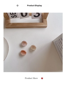 Detailed view of shell-shaped hair clips in pink and pearly white with gold linear accents