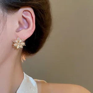 Exquisite gold floral stud earrings with cat eye stone and sparkling zircon on model
