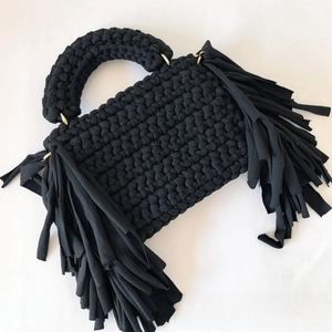 Close-up of black handmade crochet bag showing thick knit texture and side fringe details