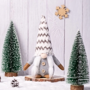 Nordic Christmas gnome plush with grey knit hat and white beard on snowy wooden background