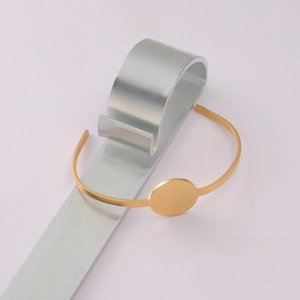 Detail of a gold-plated open bracelet with a flat round base for DIY jewelry making