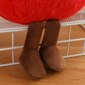 Close-up of cute plush tomato doll showing soft red fabric texture and thin brown legs