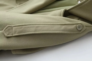 Detail of olive green woolen coat featuring a classic buttoned cuff and textured fabric
