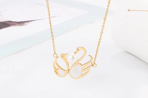 Detailansicht einer goldenen Schwan-Halskette mit eleganter Perlenmitte und Flügeln