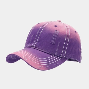 Detail of distressed purple gradient baseball cap featuring ripped fabric and white stitching