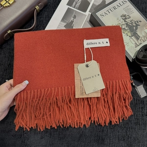 Detailed close-up of an orange tassel scarf with authentic warmth tags and lifestyle props