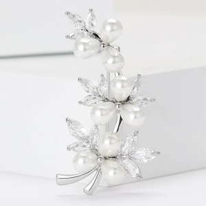 Macro detail of silver vine brooch with white pearls and sparkling cubic zirconia leaves