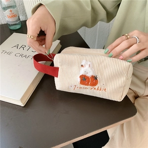 Detail der süßen Tomaten-Hasen-Stickerei auf beiger Cord-Kosmetiktasche mit roter Schlaufe