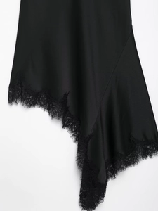 Détail de la robe en satin noir avec ourlet asymétrique et bordure en dentelle délicate