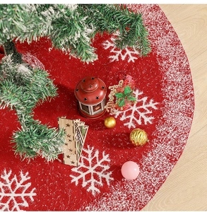 Detail of red knitted Christmas tree skirt with white snowflake patterns and festive decor