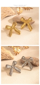 Polished gold and silver striped bow earrings displayed on natural stone