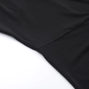 Gros plan des coutures de précision sur une robe en maille noire à épaule dénudée