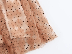 Dettaglio in tulle beige con fiori 3D e pois neri sulla superficie del vestito