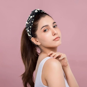 Elegant black twisted headband with pearls and rhinestones on female model