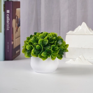 Detail of a green artificial plant in a white round pot for indoor desk decoration