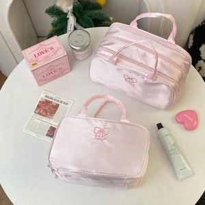 Dettaglio del set di beauty case in raso rosa con ricamo Lucky e decorazioni a fiocco