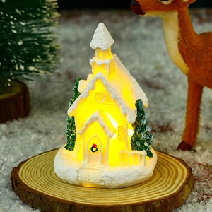 Detailed view of white Christmas resin house glowing with warm light on a wooden base