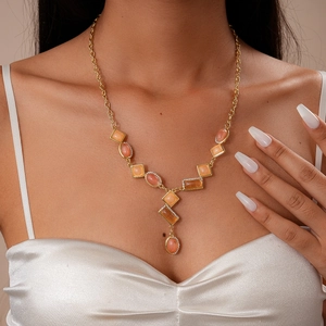 Close-up of a vintage gold-toned sweater chain with pink and orange resin gemstones