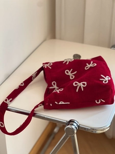 Detail shot of the red corduroy shoulder bag featuring white embroidered bow patterns