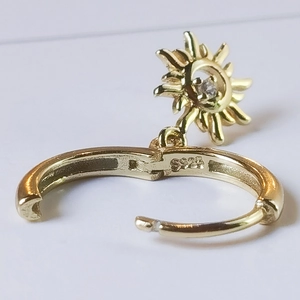 Macro shot of gold S925 sterling silver hoop earring with sun pendant and zircon stone
