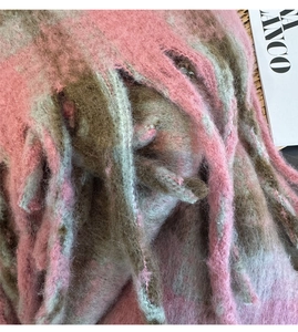 Close-up of pink and taupe mixed plaid scarf featuring soft fleece texture and tassels