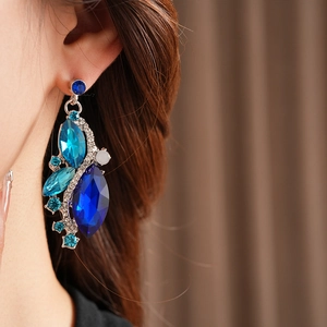 Close-up of vintage diamond-set rhombus earrings with blue crystals on model