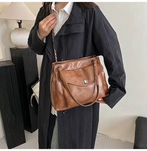 Dettaglio borsa shopper marrone con chiusura a scatto argento e tracolla a catena