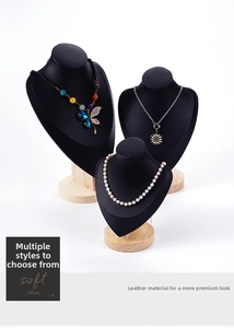 Three black leather necklace busts with wooden bases in a staggered display layout