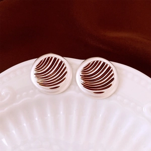 Close-up of vintage round earrings with brown striped enamel and silver-colored metal edges