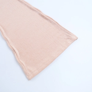 Detail of peach pink ribbed knit hem showing high-quality stitching and texture