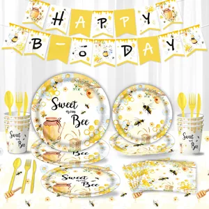Flat lay of Happy Bee Day party set including plates, cups, and honeycomb napkins