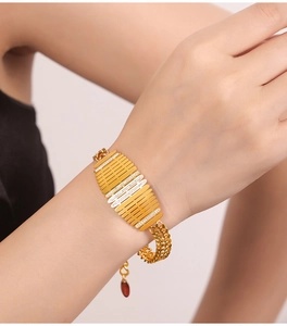 Macro shot of gold fence-style bracelet featuring crystal inlay and woven metal chain