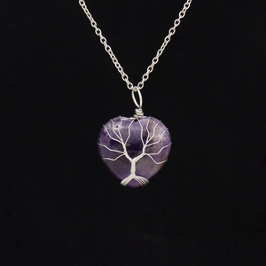 Macro shot of silver wire-wrapped tree of life design on purple heart-shaped stone pendant