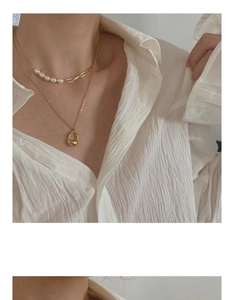 Detail of layered gold chain necklace with white pearls and irregular water drop pendant