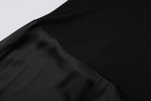 Close-up of black dress showing texture contrast between knit fabric and satin panel