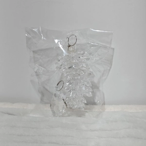 Macro detail of transparent acrylic crystal pinecone ornaments on white plush background