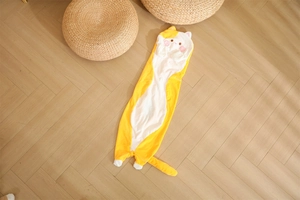 Detail of a long yellow cat plush pillow on a wooden floor in a cozy room setting