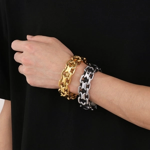 Detail showing gold and silver interlocking link bracelets on a male model's wrist