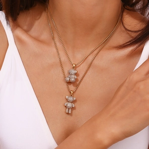 Detail of layered gold double chain necklace featuring two sparkling crystal bear pendants