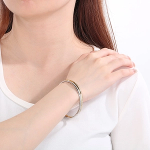 Detail of minimalist gold and silver stacked titanium steel bangles on model wrist