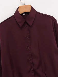 Detailed view of dark red satin shirt collar with XS size tag on a wooden hanger
