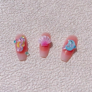 Detail of 3D sea charms including seahorse and dolphin on gradient pink press-on nails