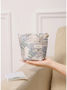 Floral embroidery portable makeup bag with gold flower zipper held in hand for travel