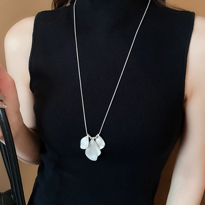 Detail of elegant white petal pendant on a silver long chain necklace for women